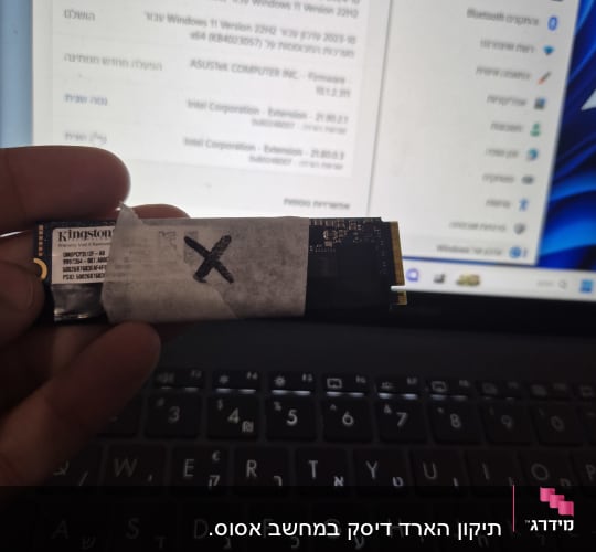 כונן SSD מוחזק מעל מקלדת מחשב נייד